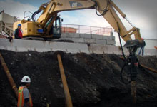 Excavator installing a pile with a Digga drive unit.