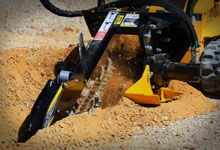 Compact loader digging with a Digga Mini Bigfoot Trencher.